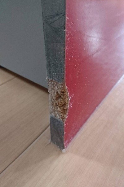 ペットにかじられた傷、キッチン下台側板の赤色の鏡面パネルです。交換工事ではなくリペアで違和感少なく仕上げます。